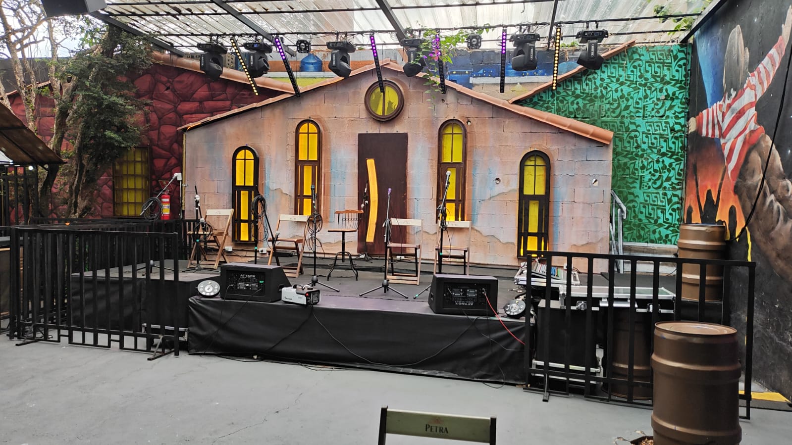 Palco cenográfico da Villa do Som com fachada de casa de pedras e rig de iluminação profissional